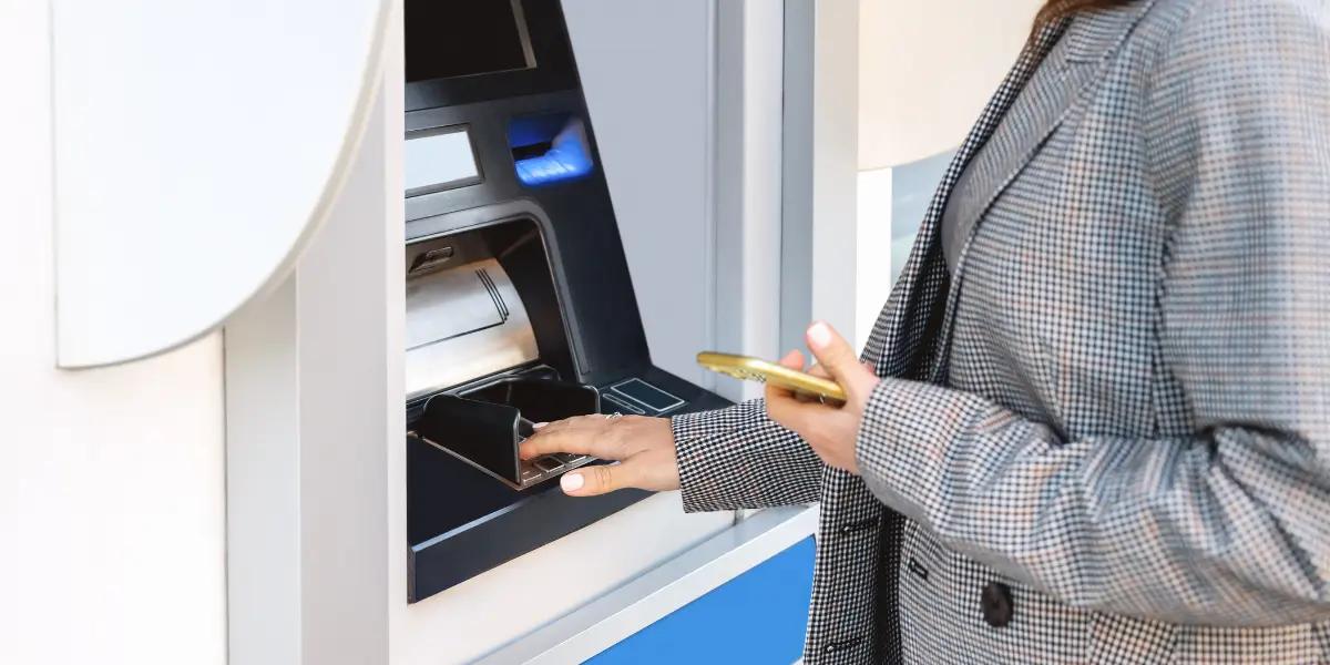 Mulher pagando boleto de aluguel no caixa eletrônico.