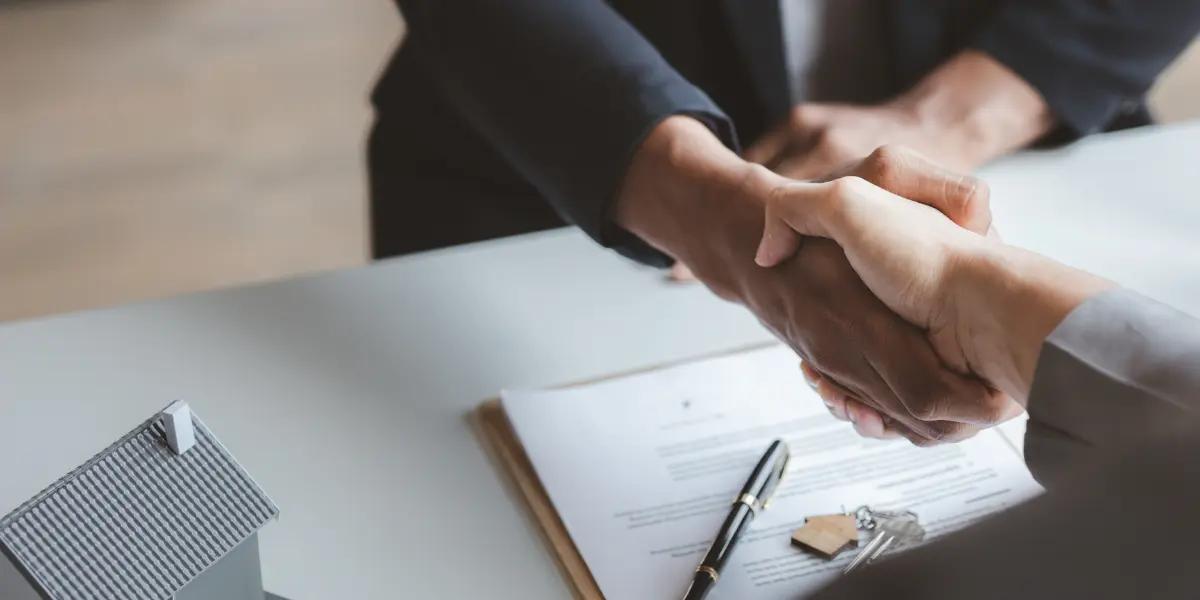 Corretor imobiliário fechando contrato de venda de imóvel penhorado com cliente.