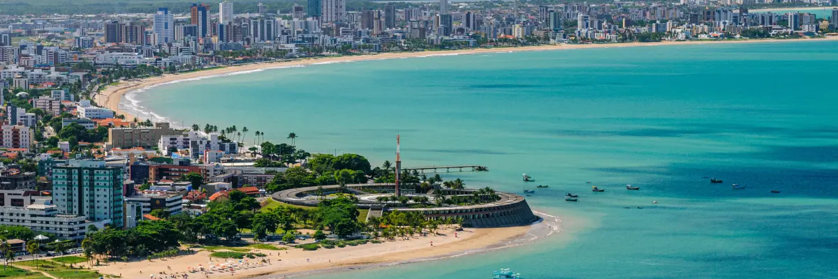 Imagem da praia de João Pessoa, com os prédios da cidade ao fundo.