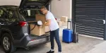 Imagem de homem colocando malas no porta-malas do carro em sua garagem.